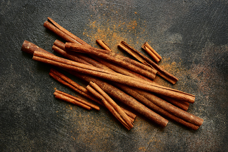 Cinnamon sticks and powder on a dark slate, stone or concrete background.Top view with copy space.の写真素材