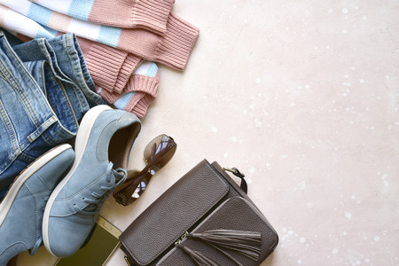 Set of women's spring, summer or autumn clothes on a light rose background - jeans, pullover,sneakers and sunglasses. Fashionable clothes for walks.Top view with copy space.の写真素材
