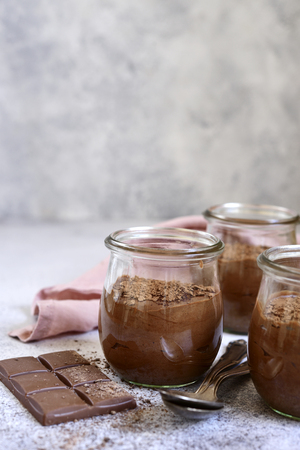 Homemade chocolate mousse in a glass jar on a light grey slate, stone or concrete background.の写真素材