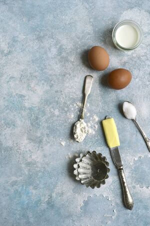 Culinary background with ingredients for baking : milk, butter,sugar, dough and egg on a light blue slate, stone or concrete table. Top view with copy space.の写真素材