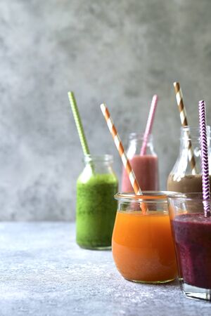 Assortment of colorful smoothies in a bottles with paper straws on a light slate, stone or concrete background.の写真素材