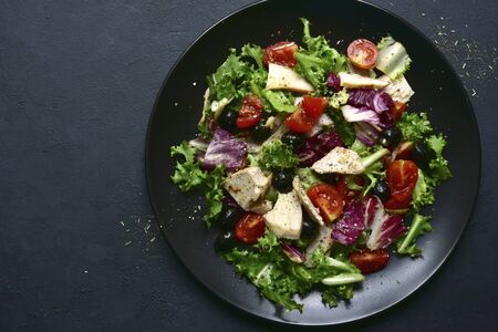 Vegetable salad with chicken and spicy citrus dressing on a white plate on a dark slate, stone or concrete background. Top view with copy space.の写真素材