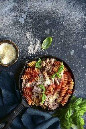 Fusilli pasta with tuna in tomato sauce in a skillet on a dark grey slate, stone or concrete background. Top view with copy space.の写真素材