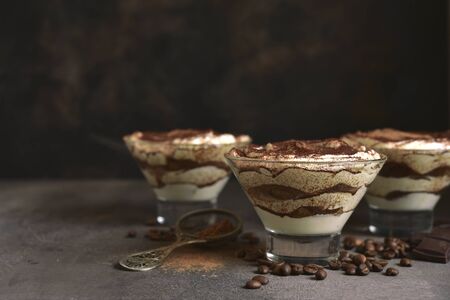 Tiramisu - traditional italian dessert from mascarpone cheese and biscuit in a glasses on a dark slate, stone or concrete background. No baked chessecake.の写真素材