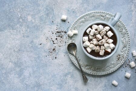 Homemade hot chocolate with mini marshmallow in a vintage cup over light blue slate, stone or concrete background.Top view with copy space.の写真素材