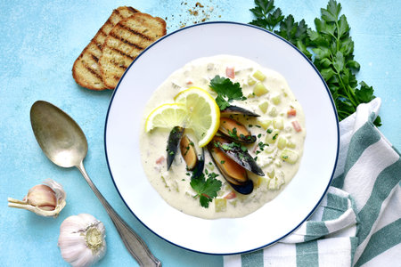 Clam chowder - traditional american soup from sea food with cream or milk in a plate on a light blue...