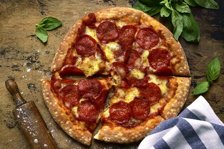 Traditional italian pizza pepperoni with salami and cheese on a rustic wooden background.Top view with copy space.の写真素材