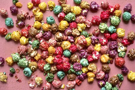 Colorful caramel candy popcorn on a pink slate, stone or concrete background. Top view with copy space.の写真素材