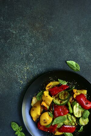 Grelled vegetables with fresh basil on a black plate on a dark green slate, stone or concrete background. Top view with copy space.の写真素材