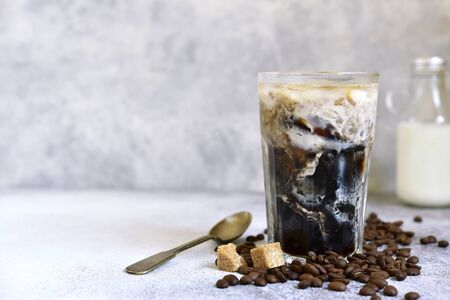 Homemade delicious iced coffee in a tall glass on a light slate, stone or concrete background.の写真素材