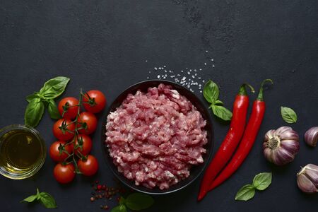 Homemade minced meat with vegetables and spices on a black slate, stone or concrete background. Top view with copy space.の写真素材