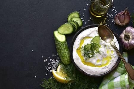 Ingredients for making tradtional greek sauce tzatziki on a black slate, stone or concrete background.  Top view with copy space.の写真素材