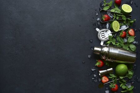 Fresh ingredients and props for making summer cold cocktail strawberry mojito on a dark slate, stone or concrete background. Top view with copy space.の写真素材