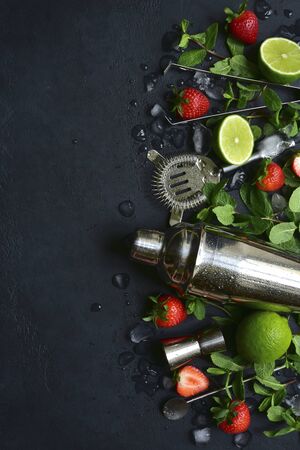 Fresh ingredients and props for making summer cold cocktail strawberry mojito on a dark slate, stone or concrete background. Top view with copy space.の写真素材