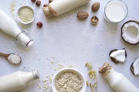 Alternative types of vegan milks in glass bottles on a white slate, stone or concrete background. Top view with copy space.の写真素材