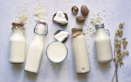 Alternative types of vegan milks in glass bottles on a white slate, stone or concrete background. Top view with copy space.の写真素材