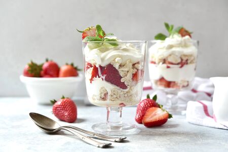 Eton mess - traditional english dessert with meringue, whipped cream and fresh berries in a glasses on a light slate, stone or concrete background. の写真素材