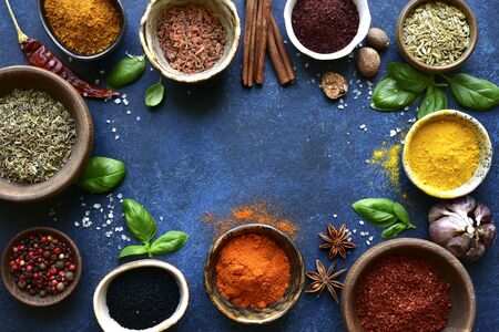 Assortment of natural organic spices in a bowls on a dark blue slate, stone or concrete background. Top view with copy space.の写真素材