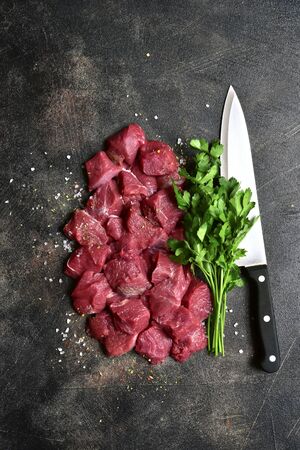 Raw organic meat ( beef or lamb ) on a dark slate, metal, stone or concrete background. Top view with copy space.の写真素材