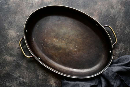 Culinary background with empty old pan on a dark slate, stone, concrete or metal background. Top view with copy space.の写真素材