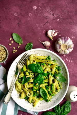 Penne pasta with green pea and basil pesto in a white bowl on slate, stone or concrete background. Top view with copy space.の写真素材
