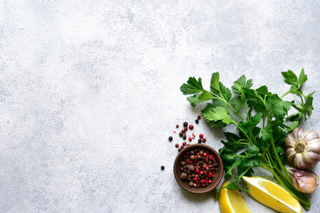 Culinary background with assortment of spices: lemon, garlic, pepper, parsley on a light slate,...