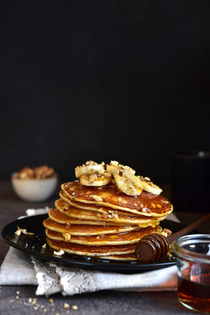 Hot delicious pancakes with honey or maple syrup on a dark background.の写真素材