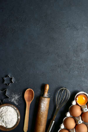 Culinary background with ingredients for baking: sugar, eggs, flour on a black slate, stone or concrete background. Top view with copy space.の写真素材