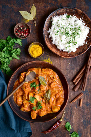Spicy chicken tikka masala with boiled rice on a dark wooden background. Top view with copy space.の写真素材
