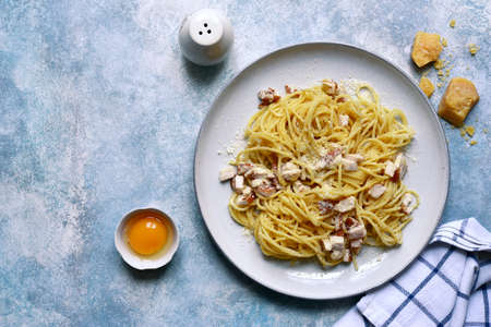 Traditional italian spaghetti alla carbonara with bacon, egg and parmesan cheese in a cream sauce on a plate on light blue slate, stone or concrete background. Top view with copy space.の写真素材