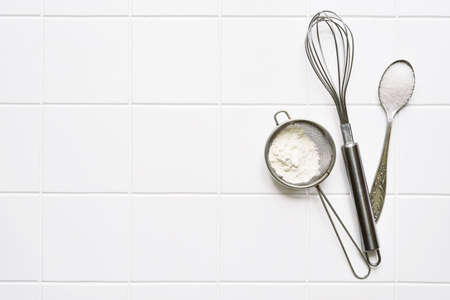 Culinary background with props and ingredients for baking: flour, egg and sugar on a white background. Top view with copy space.の写真素材