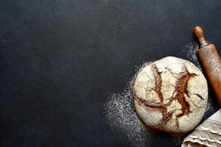 Homemade organic rye bread on a dark slate, stone or concrete background. Top view with copy space.