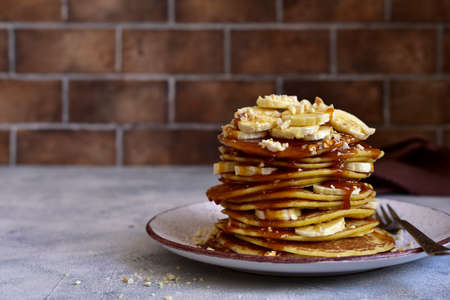Hot homemade banana pancakes with caramel sauce and nuts on a plate.の写真素材