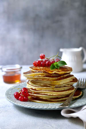 Delicious hot pancakes with fresh berries and maple syrup for a breakfast on a gray plate on light slate, stone or concrete background.の写真素材