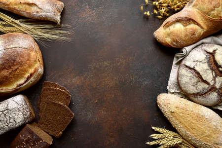 Homemade fresh baked bread with flour and ears on a dark wooden background. Top view.の写真素材
