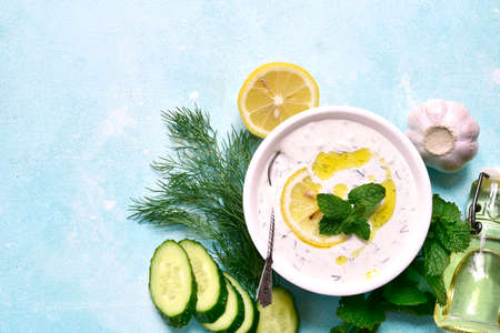 Tzatziki - traditional greek sauce from yogurt, garlic and dill in a bowl over light blue slate, stone or concrete background. Top view with copy space.の写真素材