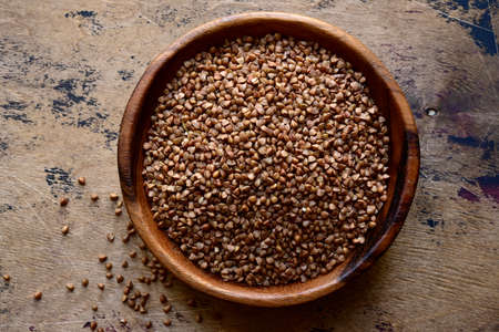 Raw organic buckwheat in a wooden bowl on a rustic background. Top view with copy space.の写真素材