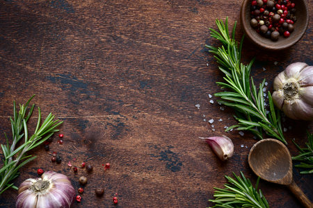Culinary background with natural spices: salt, pepper, garlic and rosemary on a dark wooden table....