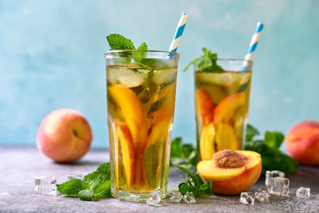 Cold summer delicious peach tea in a tall glasses on a turquoise slate, stone or concrete background.の写真素材