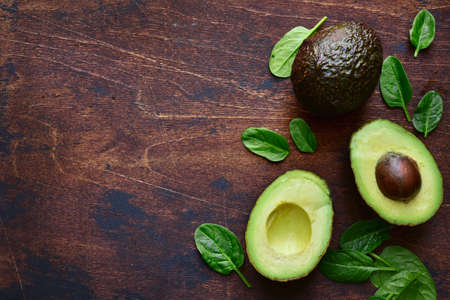 Avocado and baby spinach on a rustic wooden background. Top view with copy space.の写真素材
