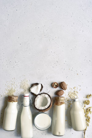 Alternative types of vegan milks in glass bottles on a white slate, stone or concrete background. Top view with copy space.の写真素材