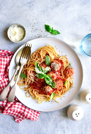 Pasta spaghetti with meat ball in tomato sauce on a plate over light gray slate, stone or concrete background. Top view with copy space.の写真素材