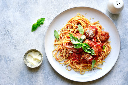 Pasta spaghetti with meat ball in tomato sauce on a plate over light gray slate, stone or concrete background. Top view with copy space.の写真素材