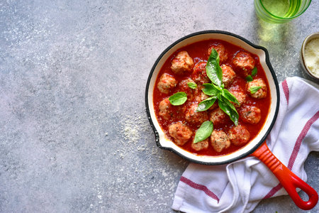 Spicy meatballs in tomato sauce in a skillet on a dark slate, stone or concrete background. Top view with copy space.の写真素材