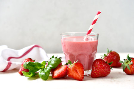 Fresh banana strawberry smoothie with basil in a glass on a light background.の写真素材