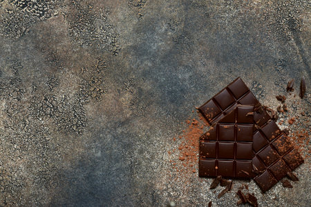 Food background with chocolate bars and cacao powder on a dark slate, stone or concrete table. Top...