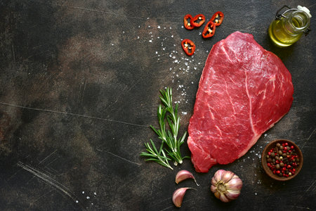 Raw organic beef steak with spices on a black slate, stone or concrete background. Top view with copy space.の写真素材