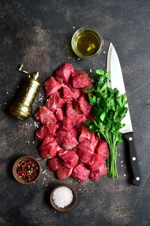 Raw organic meat ( beef or lamb ) on a dark slate, metal, stone or concrete background. Top view with copy space.の写真素材