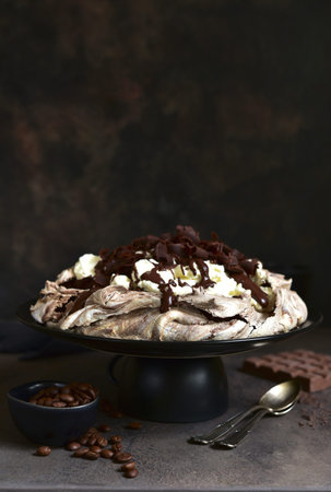 Chocolate meringue cake "Pavlova" on a dark slate, stone or concrete backgroundの写真素材