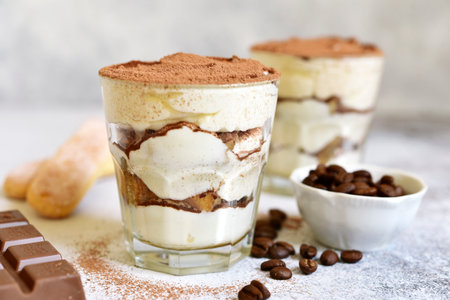 Tiramisu - traditional italian coffee dessert from mascarpone cheese and biscuit in a glass cup on a white slate, srone or concrete background.の写真素材